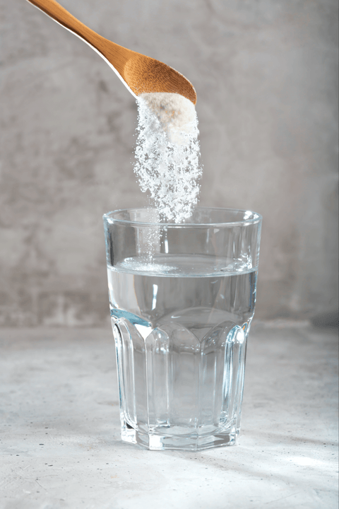 adding scoop of Just Collagen hydrolyzed marine collagen powder in glass of water