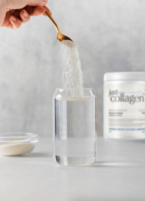 adding scoop of hydrolyzed collagen powder in glass of water